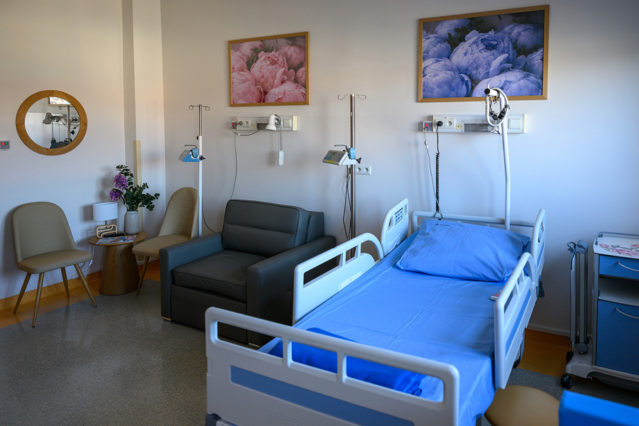 Na zdjęciu wspomniana nowa sala - łóżko szpitalne, obok rozkłądany fotel, mały stolik z krzesłami